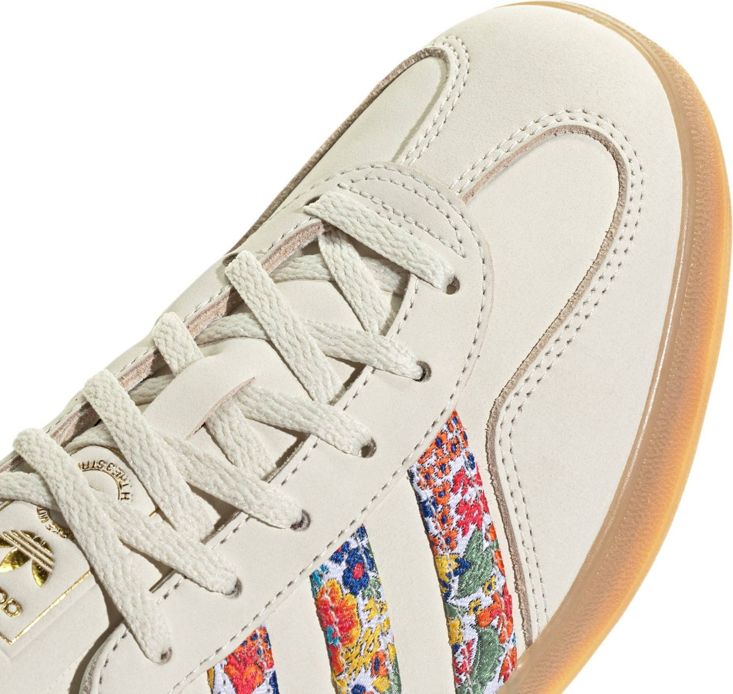 Adidas Women's Gazelle Indoor x Liberty London sneakers, featuring a cream nubuck upper with a vibrant floral embroidery pattern on the three stripes.
