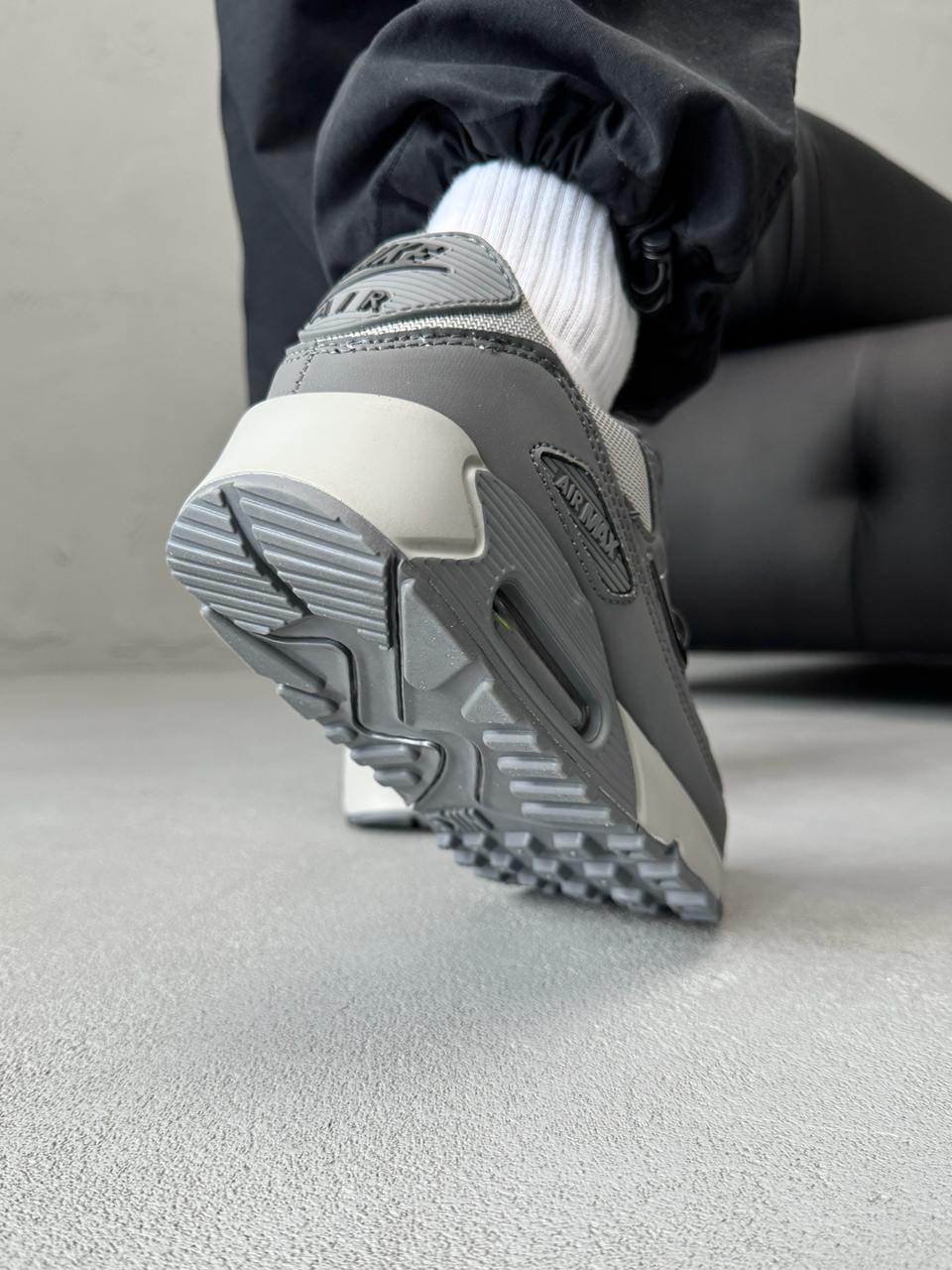 Nike Air Max 90 sneakers feature a grey upper with a polished black jewel swoosh.