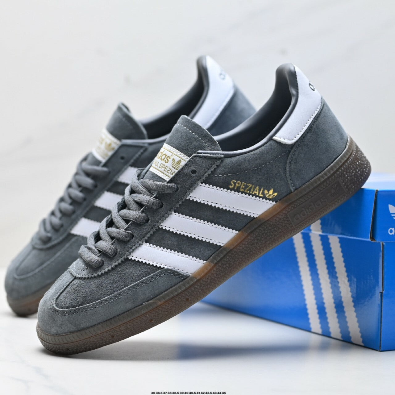 Adidas Handball Spezial sneakers, featuring a grey suede upper, white stripes, and a classic brown gum sole.