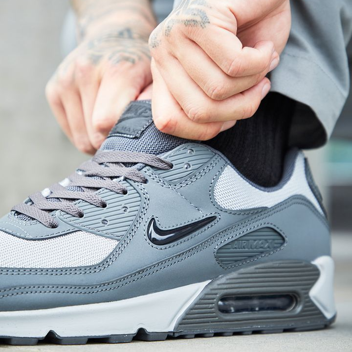 Nike Air Max 90 sneakers featuring a grey and white color scheme.