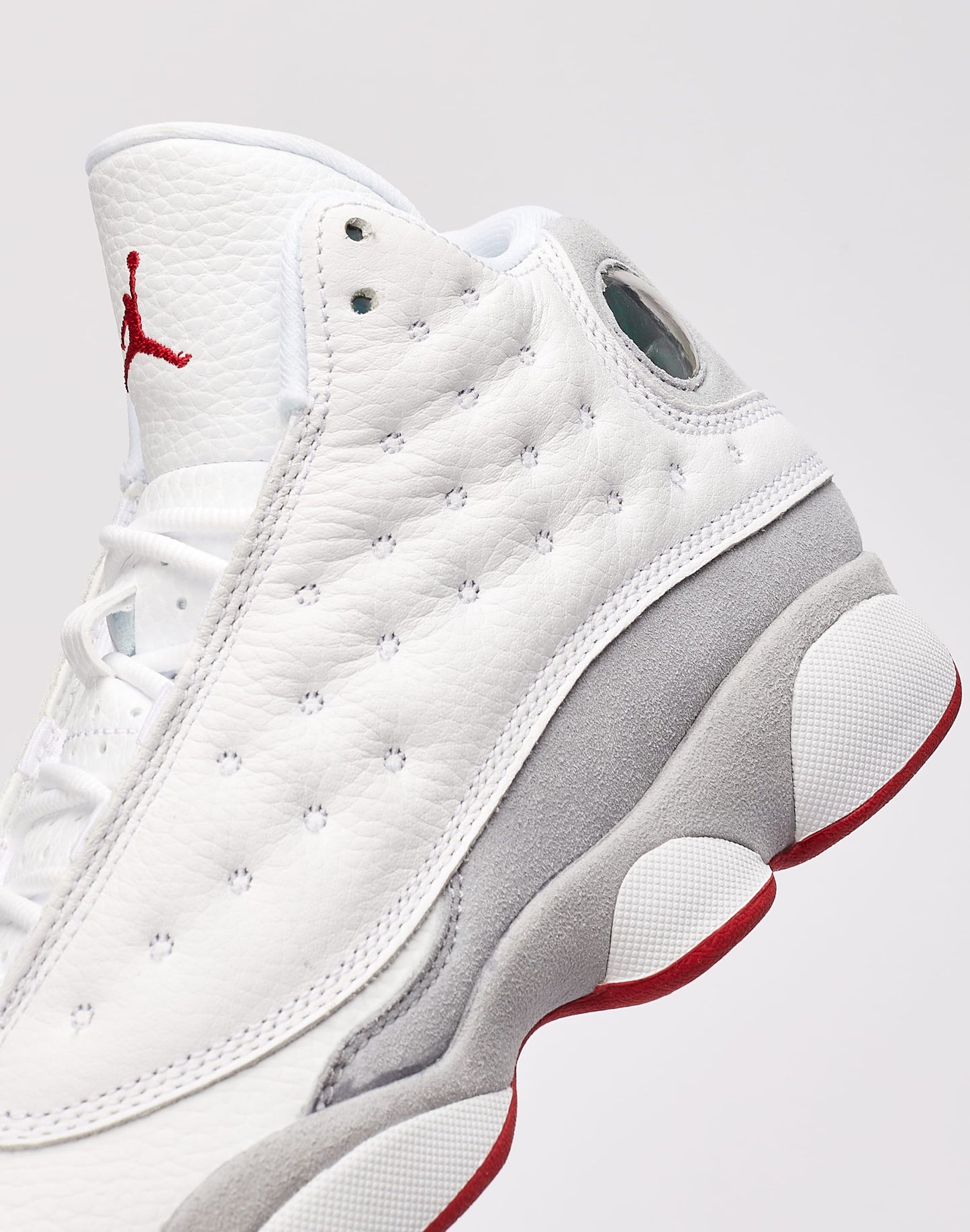 These are the Nike Air Jordan 13 Retro "Wolf Grey" sneakers, featuring a white tumbled leather upper with a signature green holographic eye on the heel.