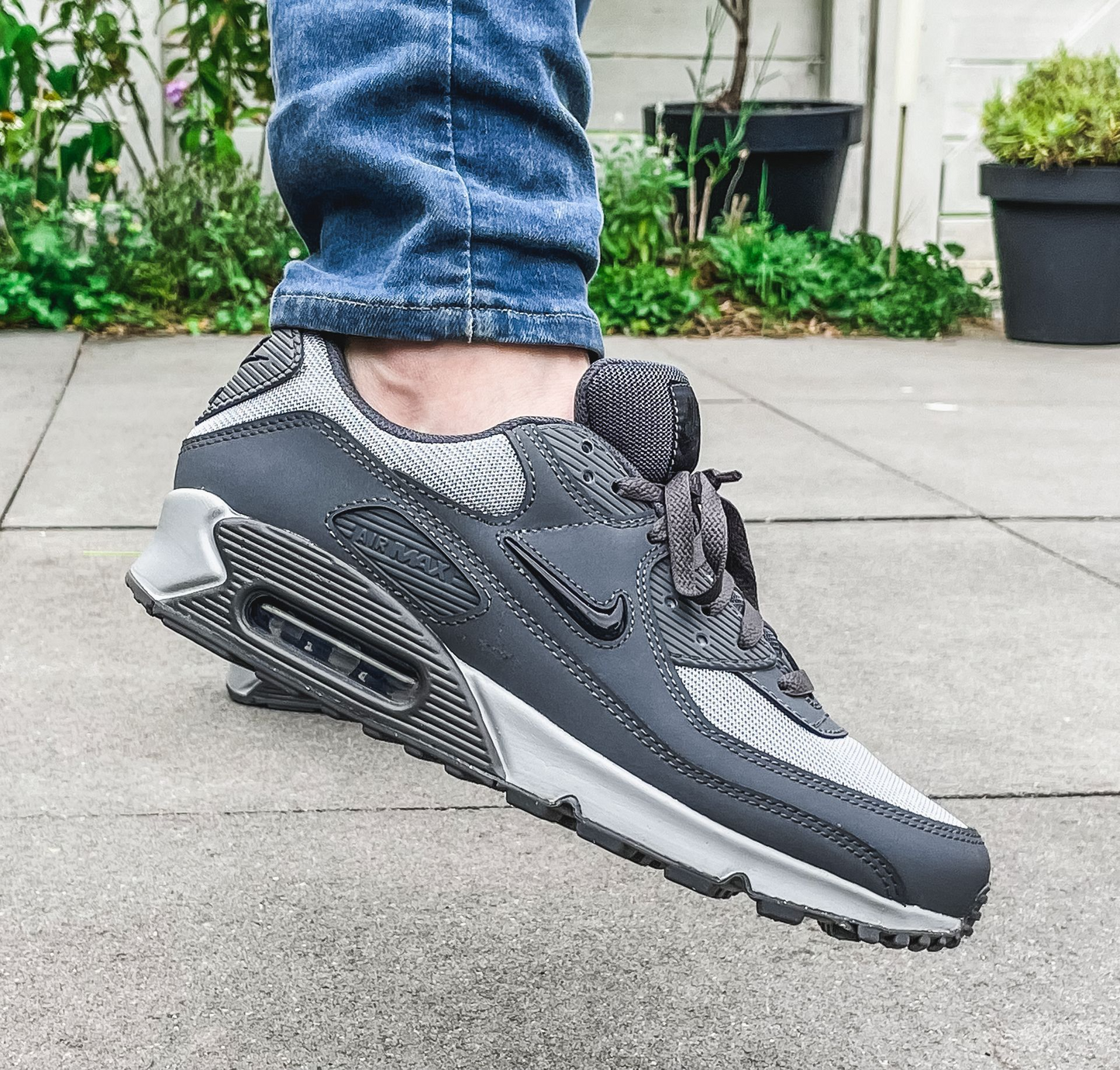 Nike Air Max 90 sneakers featuring a grey and white color scheme.
