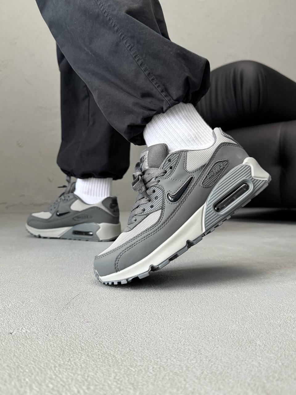 Nike Air Max 90 sneakers feature a grey upper with a polished black jewel swoosh.