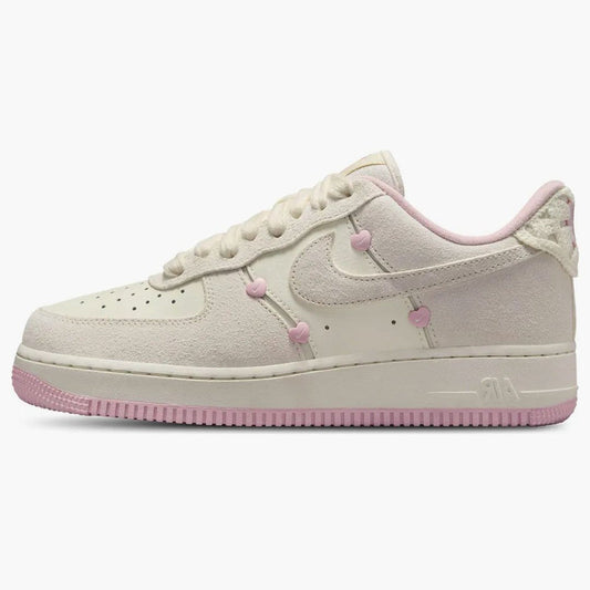 Nike Air Force 1 Low "Valentine's Day" sneakers featuring light beige suede overlays and small pink heart details along the Swoosh.
