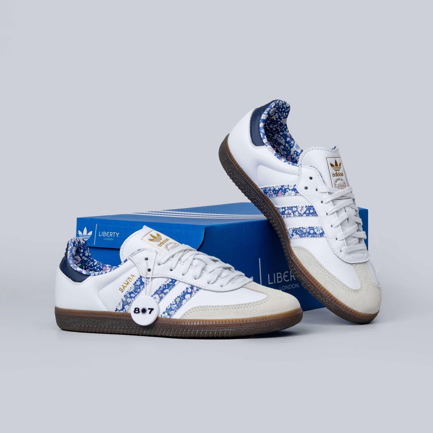 Adidas Samba Liberty LDN sneakers feature a white leather upper with blue floral-printed stripes.