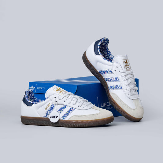 Adidas Samba Liberty LDN sneakers feature a white leather upper with blue floral-printed stripes.