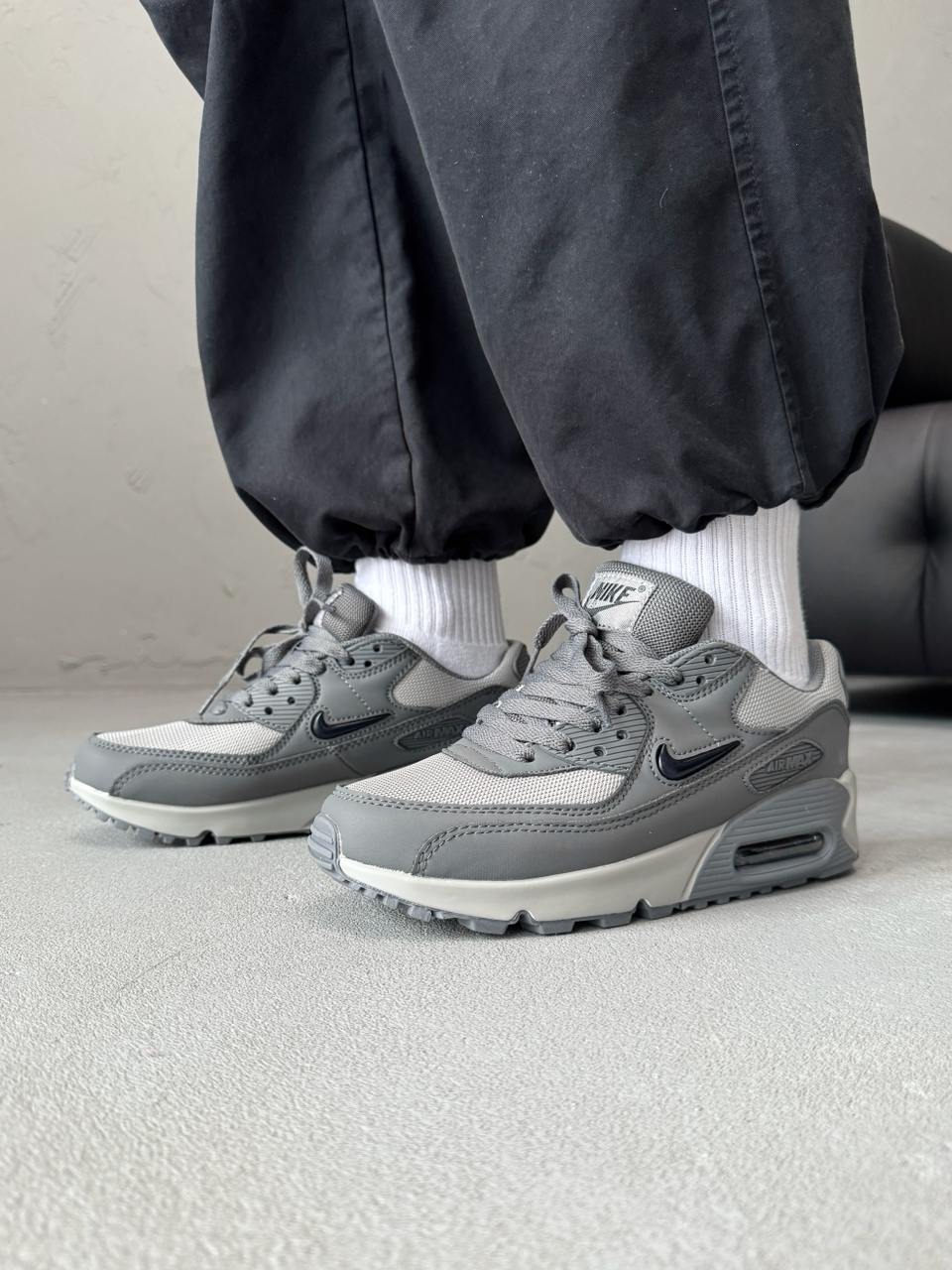 Nike Air Max 90 sneakers feature a grey upper with a polished black jewel swoosh.