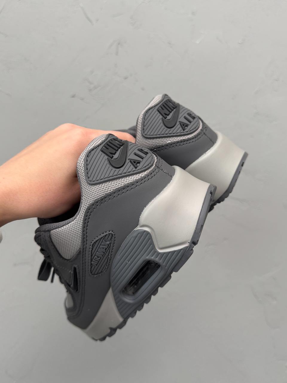 Nike Air Max 90 sneakers feature a grey upper with a polished black jewel swoosh.