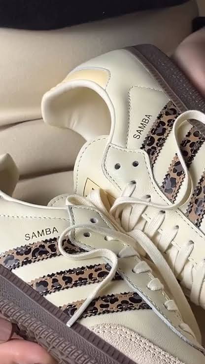 Adidas Samba OG shoes, featuring a cream-colored leather upper and a distinctive leopard print on the signature three stripes.