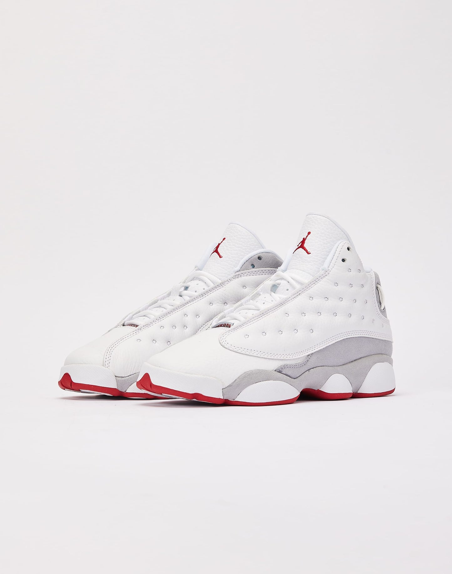 These are the Nike Air Jordan 13 Retro "Wolf Grey" sneakers, featuring a white tumbled leather upper with a signature green holographic eye on the heel.